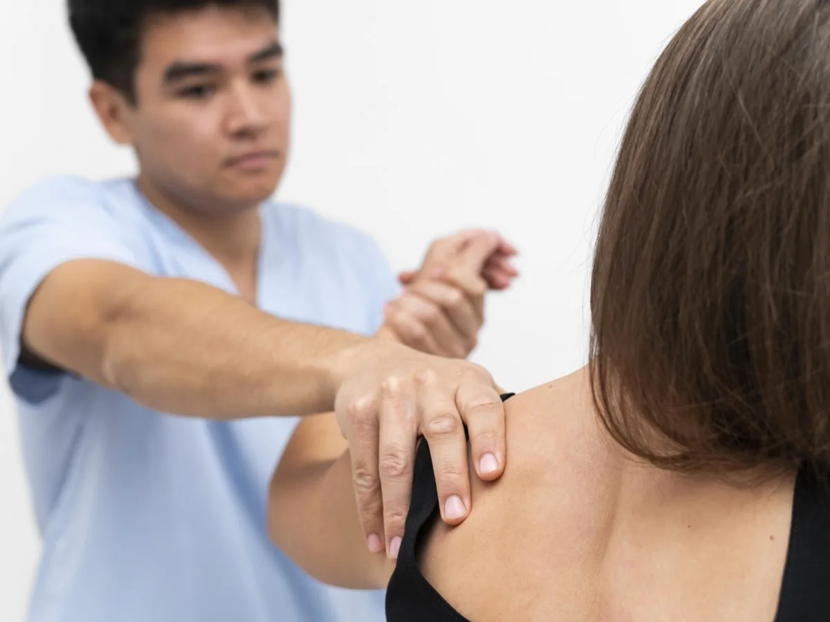นักกายภาพบำบัดใช้มือตรวจการเคลื่อนไหวของข้อไหล่ผู้เข้ารับบริการ